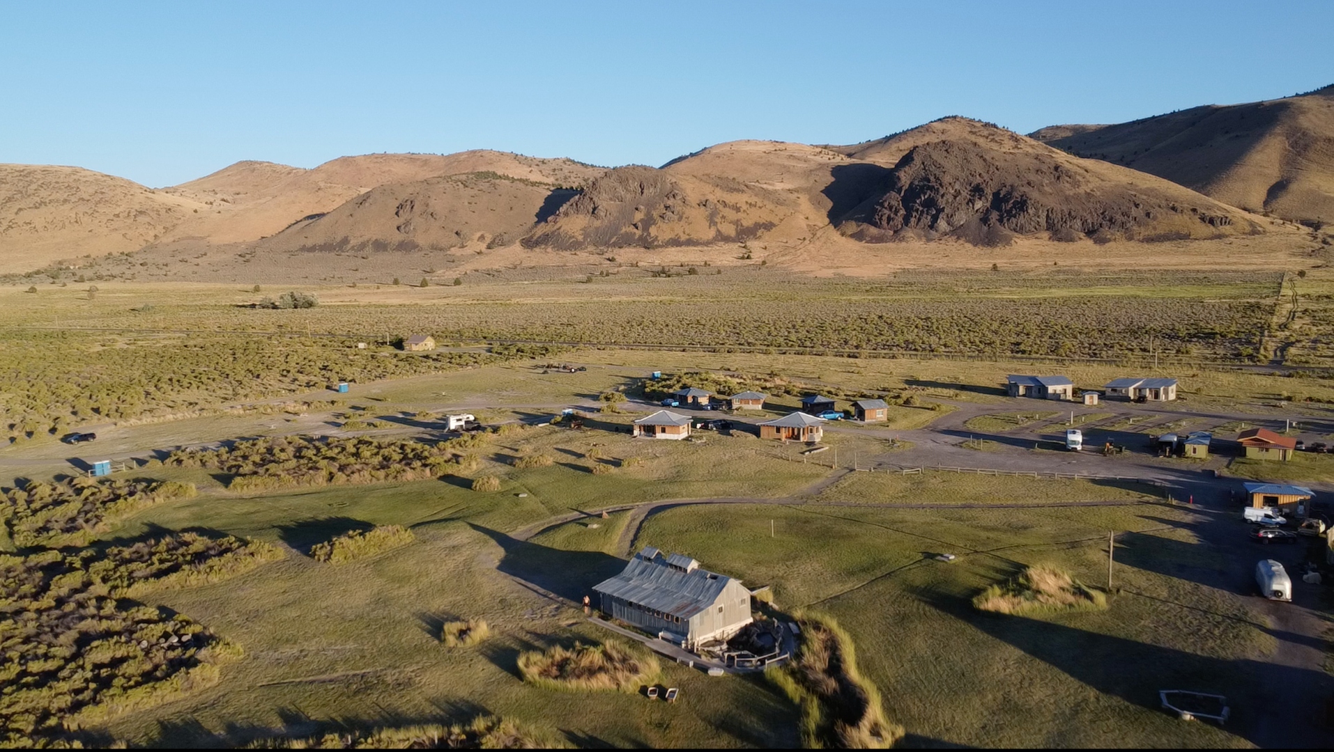 Aerial drone view of Summer Lake Hot Springs with mountains behind