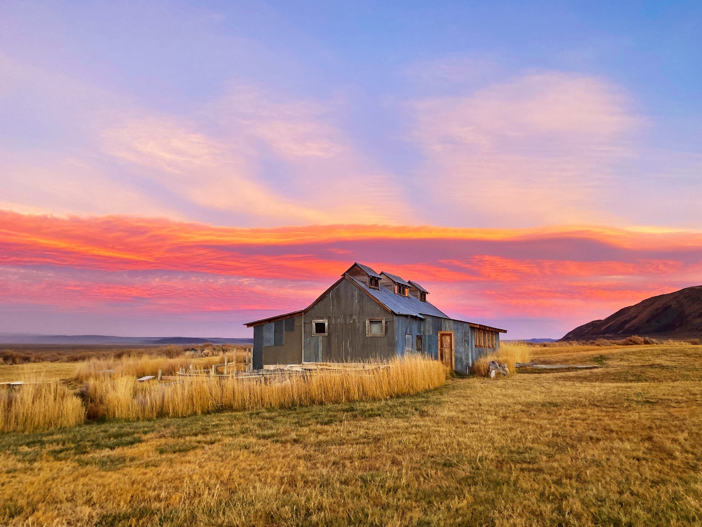 Summer Lake Hot Springs bathhouse at sunrise with vivid pink and orange sky