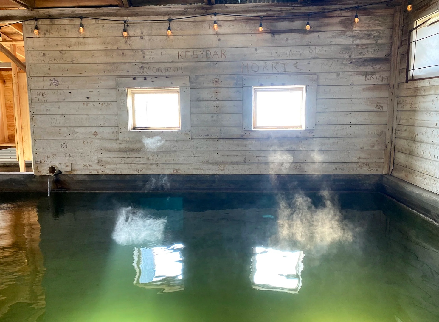 Steam rising inside the Summer Lake Hot Springs bathhouse, two windows reflecting light