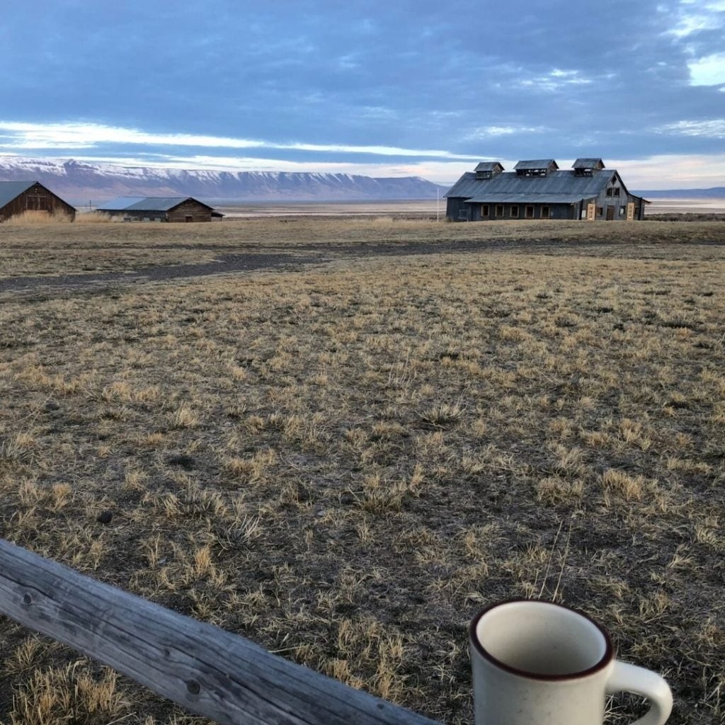 Morning coffee mug with Summer Lake Hot Springs bathhouse and snowy mountains in the distance